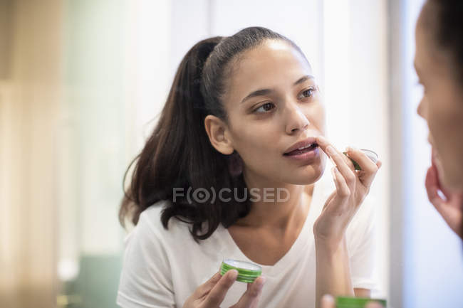 Donna che applica balsamo labbra nello specchio — Foto stock