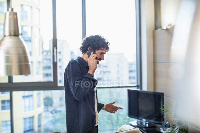 Uomo che parla su smart phone in appartamento urbano — Foto stock