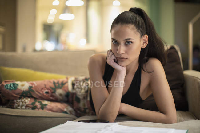 Portrait femme confiante en pyjama lire la paperasse sur le canapé du salon — Photo de stock