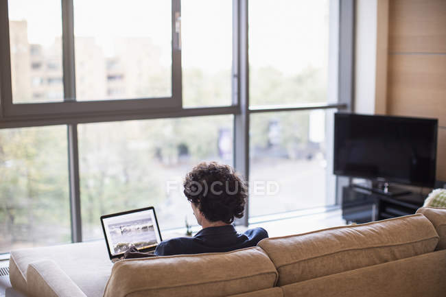 Mann benutzte Laptop auf Wohnungssofa — Stockfoto