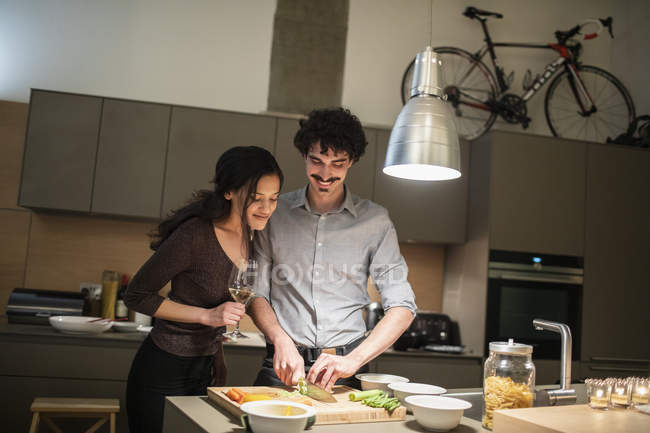 Couple cutting vegetables, cooking dinner in apartment kitchen — Stock Photo