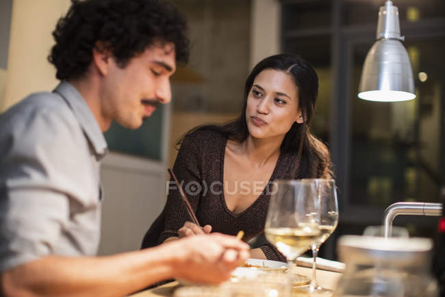 Casal jantando com pauzinhos e bebendo vinho branco em casa — Fotografia de Stock