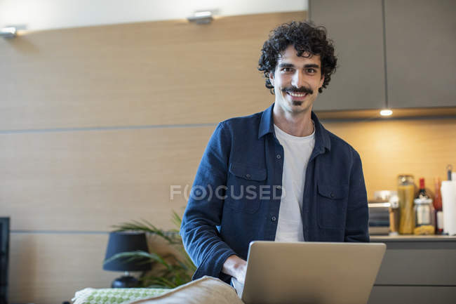 Retrato sorridente homem usando laptop na cozinha apartamento — Fotografia de Stock