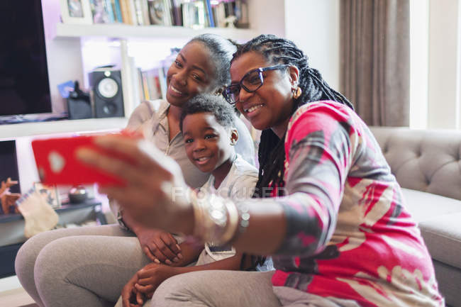 Familia multi-generación tomando selfie con teléfono de cámara en la sala de estar - foto de stock