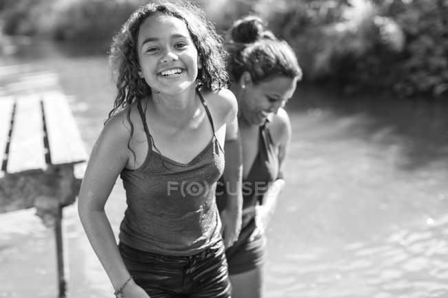 Retrato feliz, madre e hija despreocupadas en el río - foto de stock