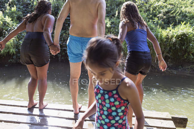 Família brincando, pulando da doca para o rio ensolarado — Fotografia de Stock