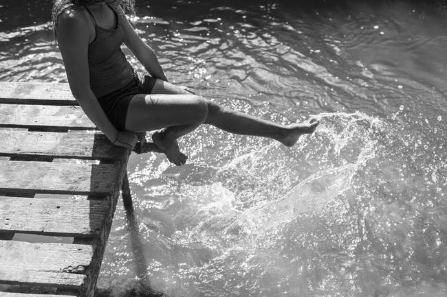 Ragazza giocosa spruzzi piedi nel fiume soleggiato — Foto stock
