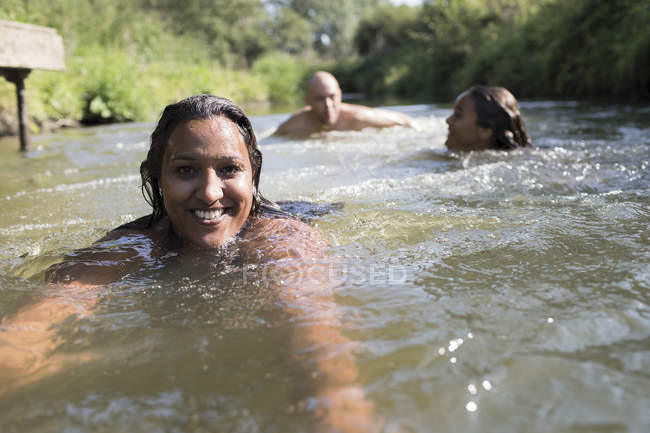 Retrato mujer feliz nadando con la familia en el río soleado - foto de stock