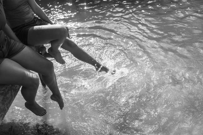 Madre e figlia spruzzi di piedi nel fiume soleggiato — Foto stock