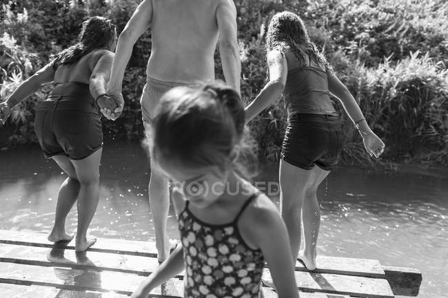Familie spielt, springt in sonnigen Fluss — Stockfoto