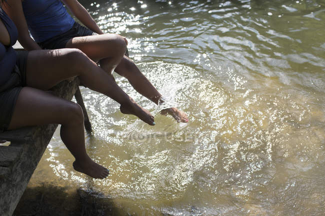 Familia salpicando las piernas en el soleado río - foto de stock
