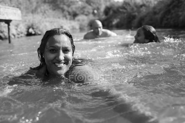 Portrait femme heureuse nageant en famille dans une rivière ensoleillée — Photo de stock