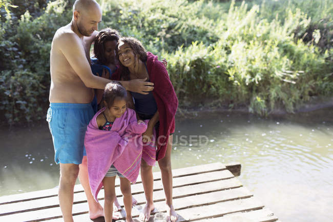 Glückliche Familie trocknet nach einem Bad am sonnigen Flussufer aus — Stockfoto