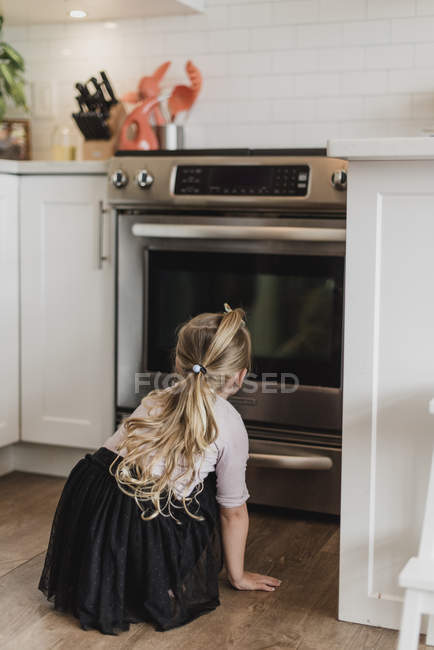 Curioso ragazza guardando forno — Foto stock