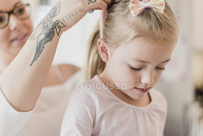 Mãe com tatuagens fixando o cabelo da filha — Fotografia de Stock