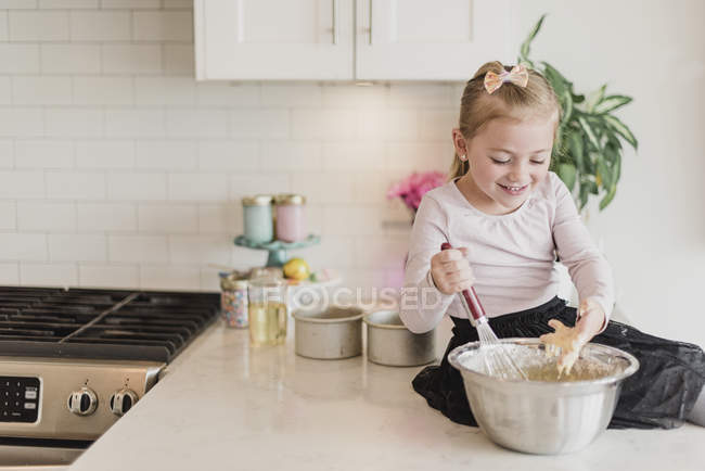 Усміхнена дівчина випікає на кухонній стійці — стокове фото
