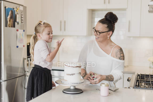 Mãe e filha bolo de decoração na cozinha — Fotografia de Stock