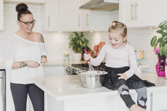 Madre e hija horneando en la cocina - foto de stock