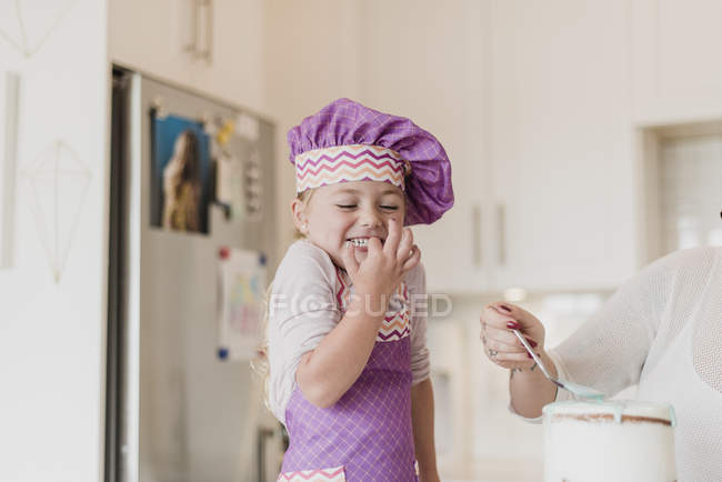 Joyeux, jolie fille dans le chapeau du chef cuisson dans la cuisine — Photo de stock