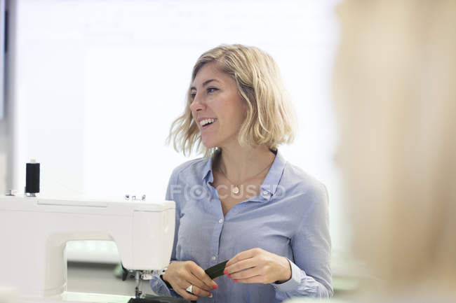 Smiling, confident female fashion designer at sewing machine — Stock Photo