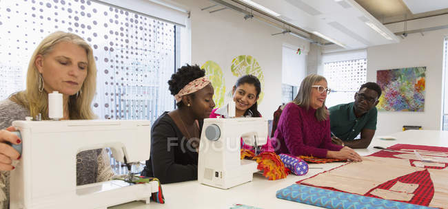 Дизайнери моди працюють над швейними машинами в студії — стокове фото