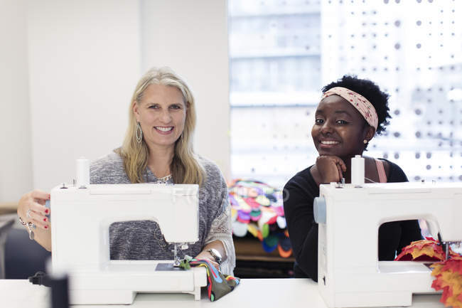Diseñadoras de moda femeninas confiadas en retratos que trabajan en máquinas de coser - foto de stock