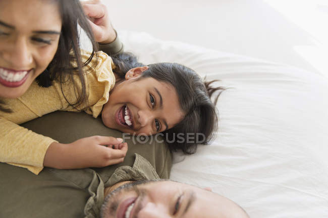Retrato pais felizes e filha abraçando na cama — Fotografia de Stock
