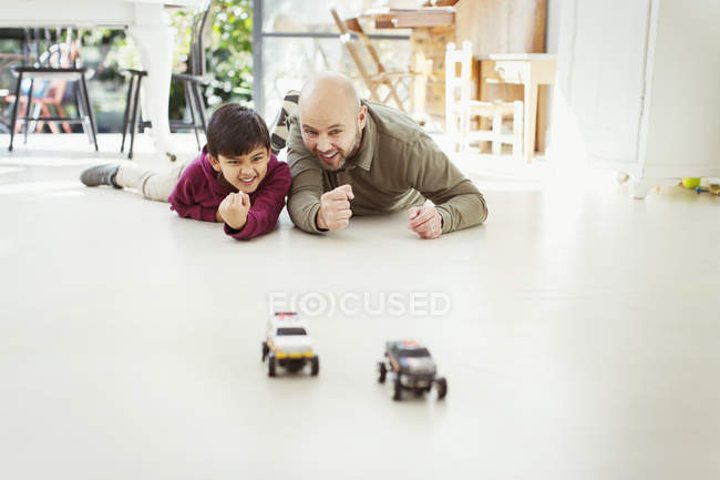 Отец и сын играют с игрушечными машинами на полу — стоковое фото