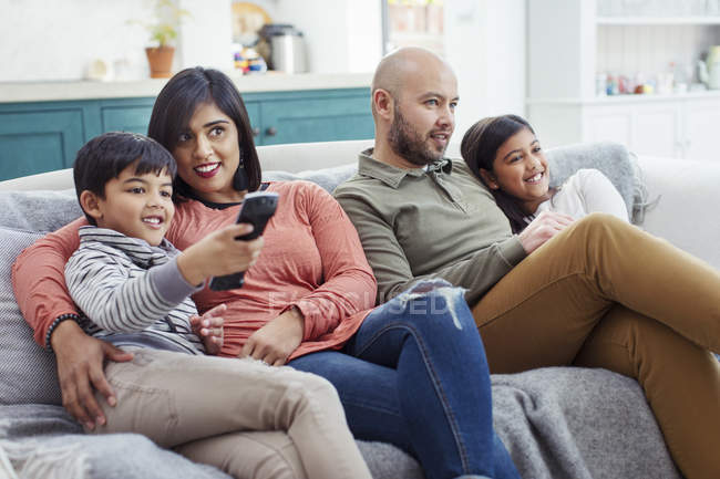Сім'я дивиться телевізор на дивані у вітальні — стокове фото