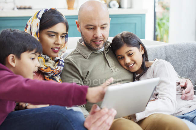 Семья с помощью цифрового планшета на диване — стоковое фото