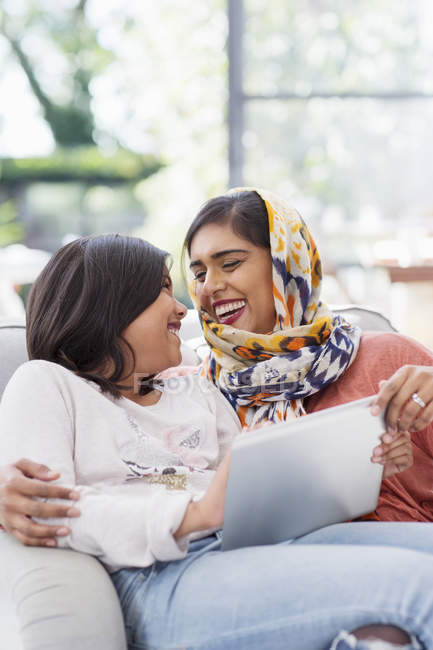Happy mother in hijab using digital tablet with daughter — Stock Photo