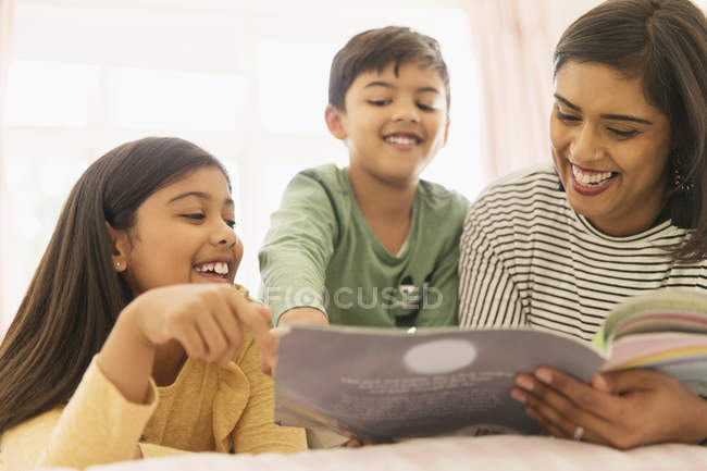 Madre e hijos leyendo libro - foto de stock