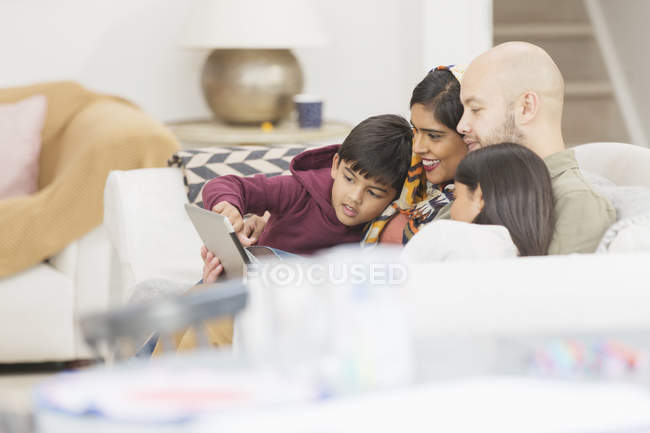 Family using digital tablet on living room sofa — Stock Photo