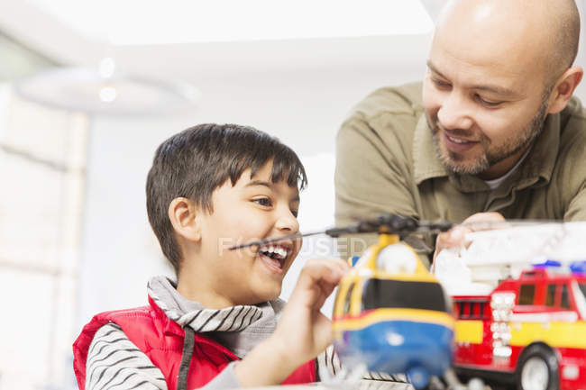 Father and son playing with helicopter and fire engine toys — Stock Photo