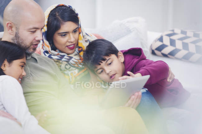 Famille utilisant une tablette numérique sur le canapé du salon — Photo de stock