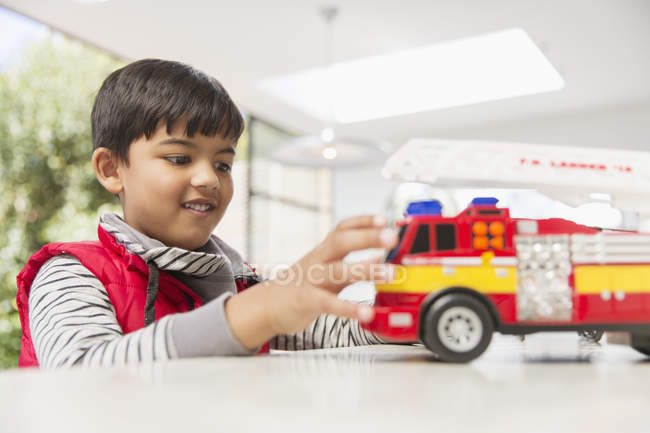 Menino brincando com brinquedo do motor de fogo — Fotografia de Stock