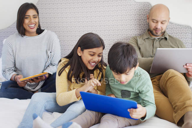 Família feliz usando a tecnologia na cama — Fotografia de Stock