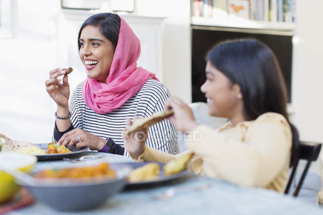 Happy mother in hijab and daughter eating dinner — Stock Photo