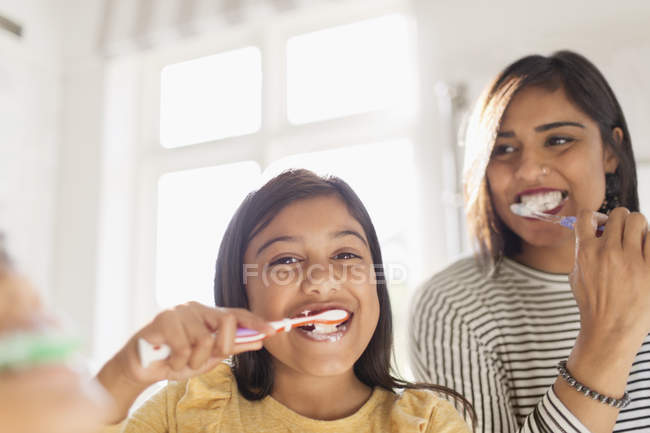 Portrait happy mother and daughter brushing teeth in bathroom — Stock Photo