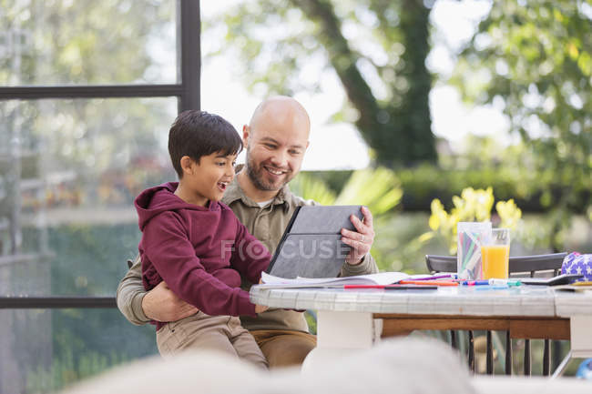 Батько і син за допомогою цифрових планшетів за столом — стокове фото