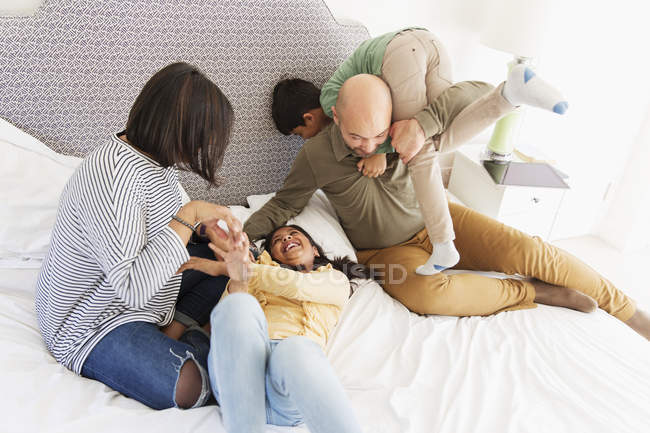 Famiglia che gioca sul letto — Foto stock