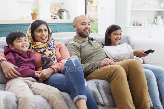 Семья смотрит телевизор на диване в гостиной — стоковое фото