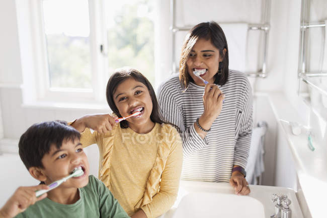 Portrait famille heureuse brossant les dents dans la salle de bain — Photo de stock
