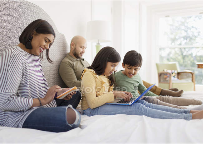 Сім'я з використанням технології на ліжку — стокове фото