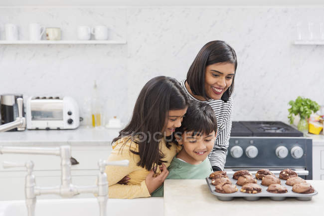 Mother and children baking chocolate muffins — Stock Photo