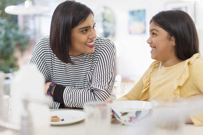 Happy mother and daughter eating breakfast — Stock Photo