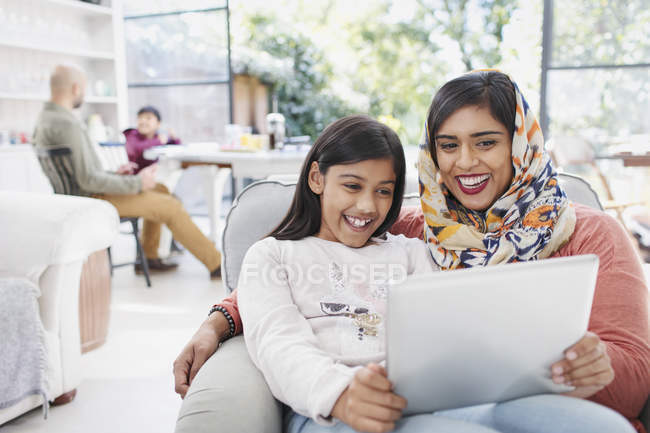 Счастливая мать в хиджабе и дочь с помощью цифрового планшета — стоковое фото