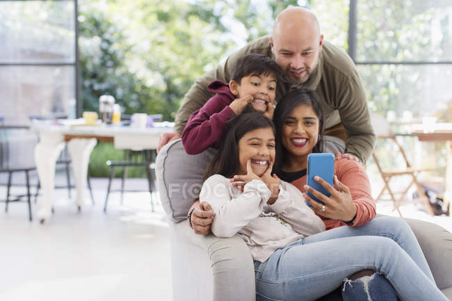 Familia juguetona tomando selfie con teléfono de la cámara - foto de stock