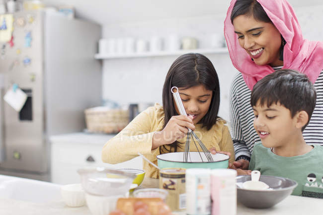 Mother in hijab baking with children in kitchen — Stock Photo