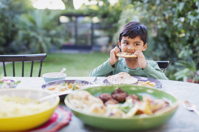 Мальчик ест наанский хлеб за обеденным столом — стоковое фото